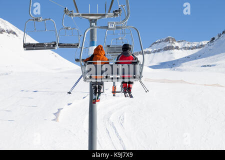 Zwei Skifahrer gehen auf der Sesselbahn und Schnee Skipiste bei Sun winter Tag. Kaukasus, Georgien, Region Gudauri. Stockfoto