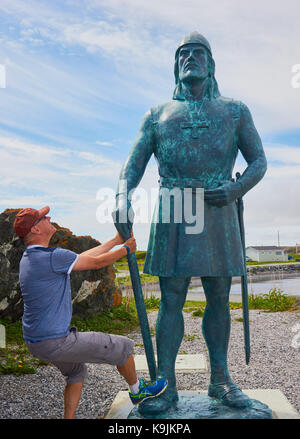 Männlicher schwedischer Tourist mittleren Alters, der auf eine 10 Fuß hohe Bronzestatue von Leif Erikson von Phillip Levine, L'Anse Aux Meadows, Neufundland, Kanada blickt Stockfoto