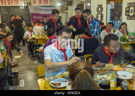 Peking, China, 23. Sep 2017. Chinesische Gäste tragen rote Schals der Jungen Pioniere in einem heißen Topf Restaurant in Peking, China, September 2017 23. Während niemand will eine Rückkehr in die Zeit der Turbulenzen, die China während der 1960er und 1970er Jahre ausgehalten, ein paar Restaurants der Leidenschaft der Revolution lebendig mit ihren kommunistischen halten - kitsch Dekor und sozialistischen Song-und-Tanz zeigt. Die chinesischen Zeichen an der Wand lesen ' Gut gut studieren, Tag für Tag bis" - Zitat von Mao. Lou Linwei/Alamy leben Nachrichten Stockfoto