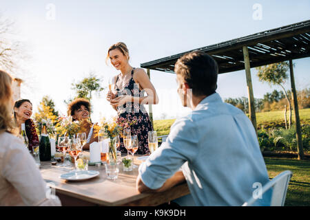 Frau eine Rede mit Freunden im Freien. Junge Menschen feiern einen besonderen Anlass in einem Gartenrestaurant. Stockfoto