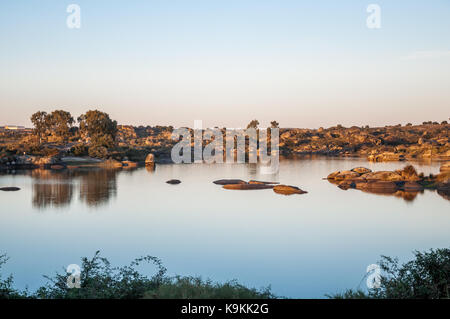 Sonnenuntergang über den Teich von naturdenkmal Los Barruecos in Malpartida de Cáceres, Extremadura, Spanien. Die Landschaft spiegelt sich im Wasser, Stockfoto