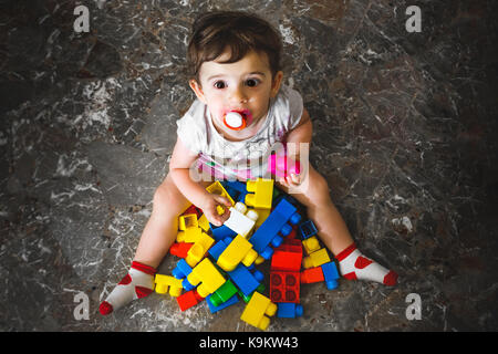 Neugeborene spielen Bausteine - bunte Spielzeug Steine - oben Blick auf ein Baby spielen mit Spielzeug Steine - kleines Kind spielen auf dem Boden Stockfoto