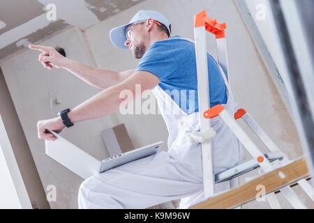 Kaukasische Bau Umbau Arbeitnehmer erklären, seine Ideen bei der Verwendung von Laptops mit umgestaltete Innenraum gerenderte Bilder. Stockfoto