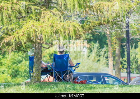 Paar sitzen im Schatten in der Nähe von einem Parkplatz auf einem schönen Anfang Herbst Abend. Stockfoto