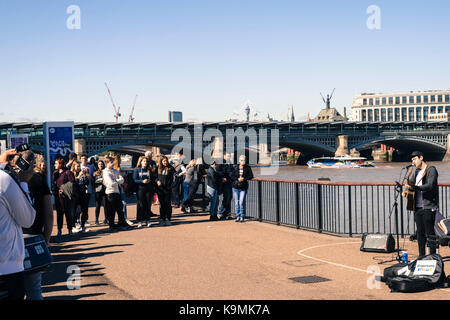 Street Performer oder Gaukler auf Bankside Southwark, London, Vereinigtes Königreich, das Unterhalten einer Masse von Menschen gegen die Themse mit Blackfriars Rai Stockfoto