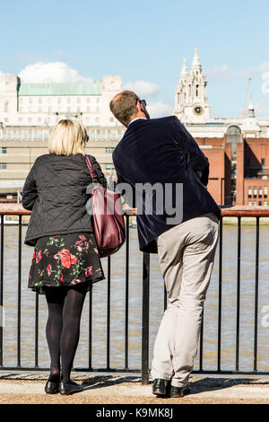 Beiläufig Dressing Smart CoupleTalking oder Chatten stehend geniessen Sie den Blick vom Ufer der Themse in Bankside Southwark London United Ki Stockfoto