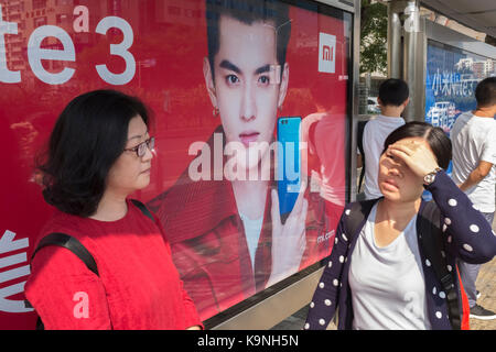 Chinesischen Pkw warten Bus vor der Anzeigentafel Kris Wu, Neue Xiaomi ist endorser. Stockfoto