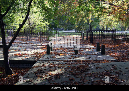 Ein alter Friedhof mit Laub auf die Grabsteine und Sonnenlicht fällt durch die Bäume Stockfoto