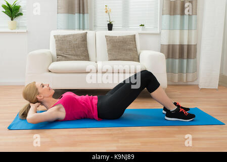Junge Frau, Übung im Haus Stockfoto