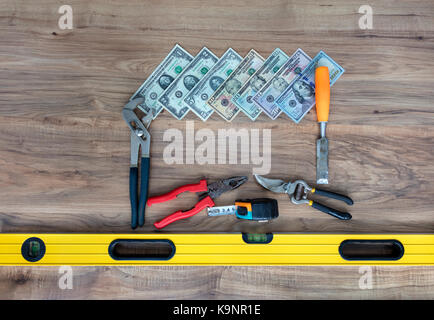 Alte Werkzeuge und eine Reihe von Dollarnoten auf einem Holztisch close-up Stockfoto