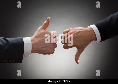 In der Nähe von zwei Geschäftsleute, die Hände sichtbar und Daumen hoch, Daumen runter Zeichen Stockfoto