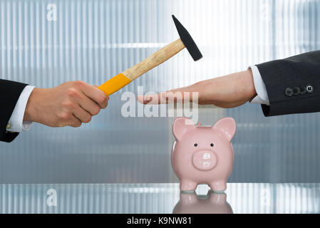 Nahaufnahme der Geschäftsmann Hände speichern Sparschwein aus Hämmern Stockfoto