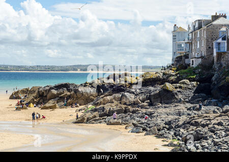 Felsen und Sand bei Ebbe in der Nähe von Porthminster Strand mit Hotels auf einer Klippe, St Ives, Cornwall, England, Großbritannien Stockfoto