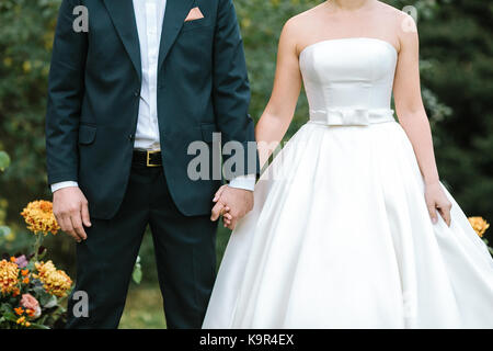 Mode, Event, Anlass Konzept. hinreißend Paar junge Liebhaber in der Hochzeit Anzüge gekleidet, formschöne Braut, die in der wunderbaren Kleid der klassischen Stil, Verlobter trägt Elegantes Kostüm Stockfoto