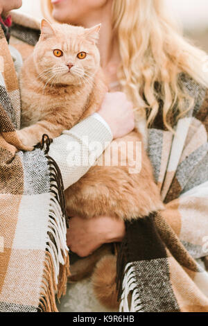 Tiere, Liebe, Natur, Herbst Konzept. paar Liebhaber in Plaid sorgfältig mit ihren prächtigen Ingwer Katze, hat tolle Augen in der Farbe von Orange gewickelt Stockfoto
