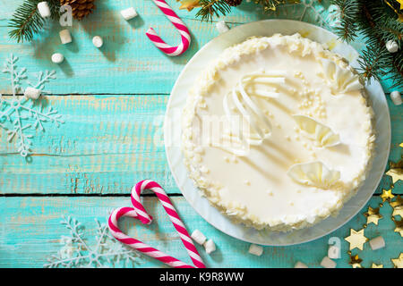 Weihnachtskuchen mit Sahnehäubchen mit weißer Schokolade auf festlichem weihnachtshintergrund. Stockfoto