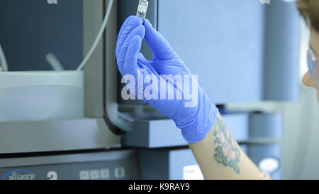 Medizinisches Labor Zentrifuge. Eine Wissenschaftlerin lasten Glasfläschchen mit Flüssigkeit in einer Zentrifuge in einem Labor. Wissenschaftler Laden einer Probe zu zentrifugieren. Frau Laboratory Assistant richtet PCR-Test micro Röhren in einer Zentrifuge. Stockfoto