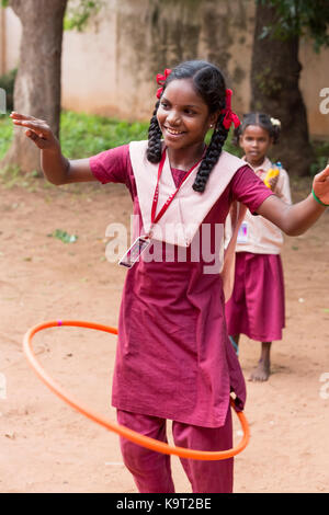 PONDICHERY, PUDUCHERY, Indien - SEPTEMBER 04, 2017. Junges Kind mit einheitlichen spielt mit Hula Hoop in der Schule, im Freien, als Sport. Stockfoto