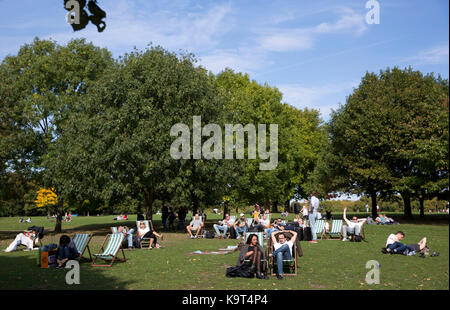 Menschen nehmen Sie ein Sonnenbad auf den Liegestühlen im Hyde Park, Central London, als Menschen im Süden Osten vorhergesagt genießen Sie Höhen von 22-23 C durch Sonntag Nachmittag. Stockfoto