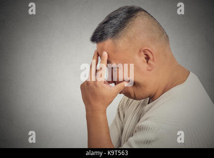 Closeup Seite Profil Portrait traurig gestört betonte im mittleren Alter Mann mit Kopf mit der Hand wirklich über etwas deprimiert isoliert grauen Hintergrund. Stockfoto