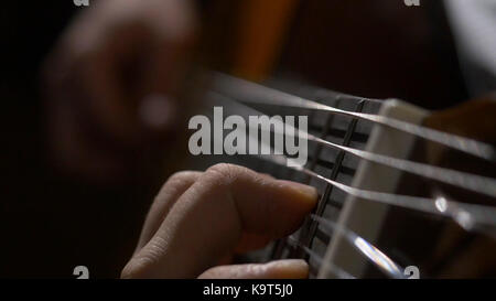 Nahaufnahme von Gitarrist Hand spielen akustische Gitarre. Nahaufnahme von einem Mann mit seinem Finger auf die Bünde der Gitarre spielen Stockfoto