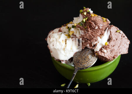 Nahaufnahme der Schüssel mit Schokolade, Rhum und Pistazieneis auf schwarzem Hintergrund. Stockfoto