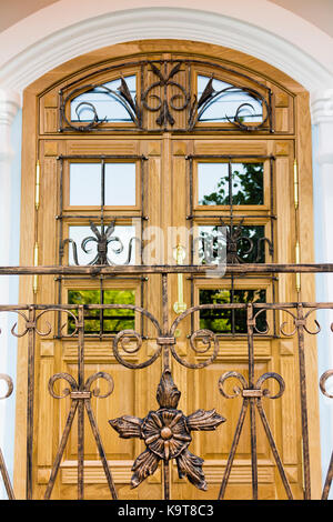 Eine hölzerne Eingangstür eines Familie brownstone Home. Tür wird durch einen Bogen, twin Geländer gerahmt, und Blumentöpfe. Stockfoto