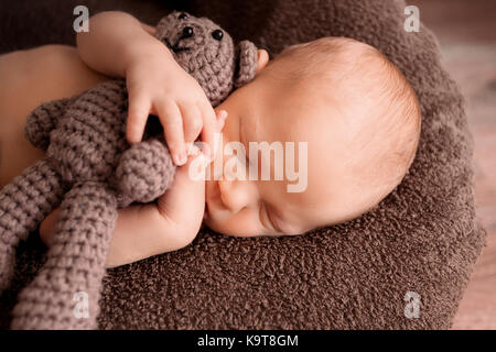 Neugeborene schlafen in einem schönen Stellen mit einem kleinen Bären Stockfoto