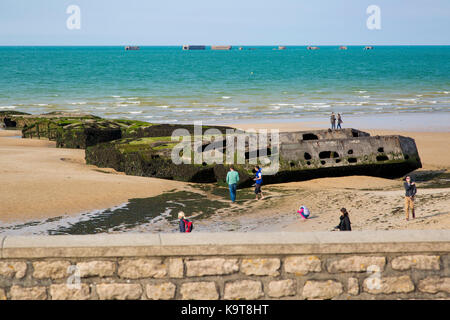 Touristen anzeigen Mulberry Hafen caissons (temp D-Tag Hafen) am Strand von Arromanches-les-Bains, Calvados, Normandie, Frankreich Stockfoto