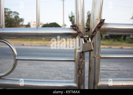 Goldene Vorhängeschloss mit Kette auf einem chainlink Fence verwendet. Selektiver Fokus ist auf das Vorhängeschloss. Stockfoto
