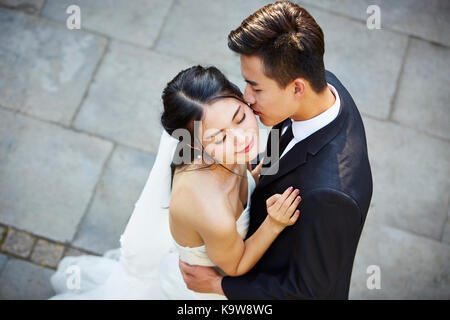 Junge asiatische Braut und Bräutigam umarmen Küssen tanzen in Open Air, hohe Blickwinkel betrachten. Stockfoto