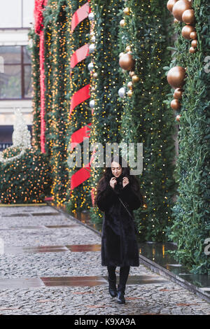 Glückliche Frau wandern in einem schwarzen Nerz Mantel in Stadt, schön für das Neue Jahr eingerichtet Stockfoto