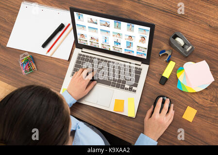 Hohe Betrachtungswinkel der Geschäftsfrau sucht in Bild auf dem Laptop am Schreibtisch Stockfoto