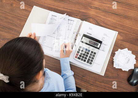 Geschäftsfrau, die Berechnung der Steuer am Schreibtisch mit Rechner im Büro Stockfoto