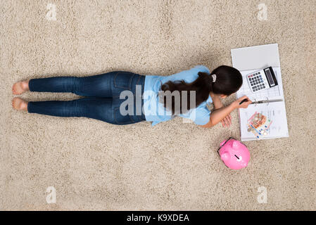 Junge Frau liegt auf dem Teppich, Berechnung zu Hause Stockfoto
