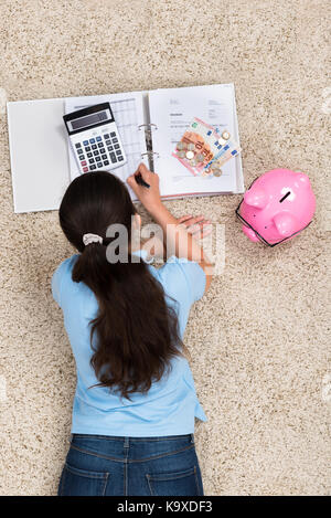 Junge Frau liegt auf dem Teppich, Berechnung zu Hause Stockfoto