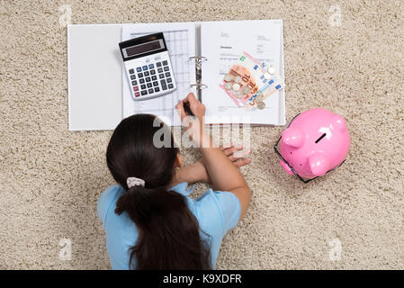 Junge Frau liegt auf dem Teppich, Berechnung zu Hause Stockfoto