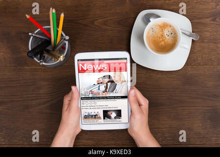 Nahaufnahme der Person Hände halten Handy News am Schreibtisch Stockfoto