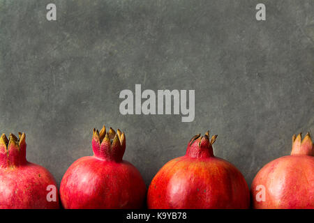 Reife rote lebendigen organischen Granatäpfel in Grenzregionen auf schwarzen Stein Hintergrund poster Grußkartenvorlage banner Herbst Thanksgiving kopieren angeordnet Stockfoto