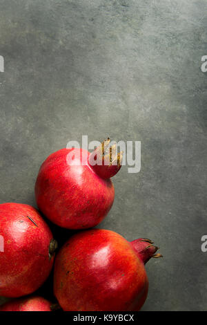 Reife rote lebendigen organischen Granatäpfel an schwarzen Stein Hintergrund poster Grußkartenvorlage banner Herbst Thanksgiving Kopie Raum Stockfoto