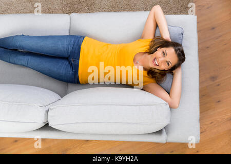 Blick von oben auf eine schöne und glückliche junge Frau liegt auf einem Sofa Stockfoto