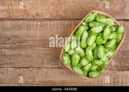 Frisches Grün für Hopfen in Korb auf Holztisch mit Kopie Raum Ansicht von oben. Hopfendolden für Bier. Zutat für die Zubereitung von Stockfoto