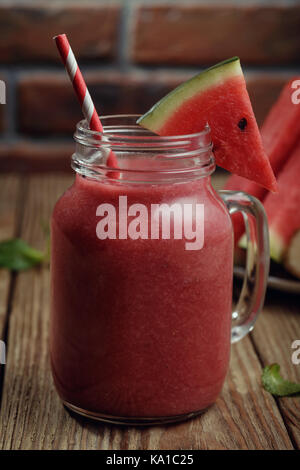 Frisch Smoothies aus Stücken von Wassermelone und eine Banane in einem Glas auf einen hölzernen Tisch Stockfoto