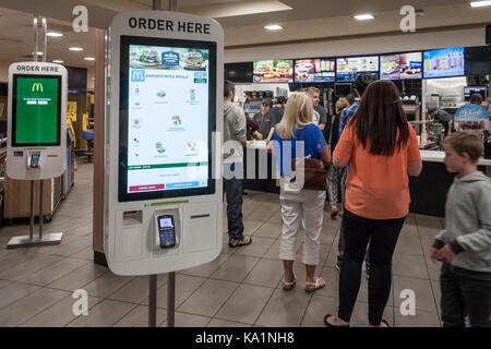 Kunden queue in einem McDonalds Restaurant ignorieren neue Selbstbedienungsautomaten. Stratford-upon-Avon, Warwickshire, England, GB, UK. Stockfoto