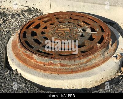 Rostigem Eisen Mannloch in Asphalt Oberflächen Stockfoto