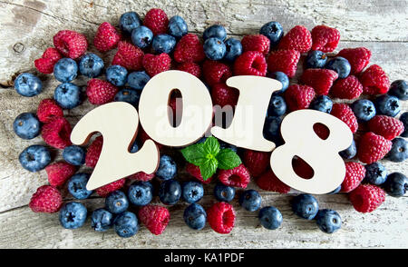 Jahr 2018 mit Blaubeeren und Himbeeren auf einer hölzernen Hintergrund. top View Stockfoto