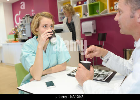 Arzt und Krankenschwester diskutieren während der Kaffeepause Stockfoto