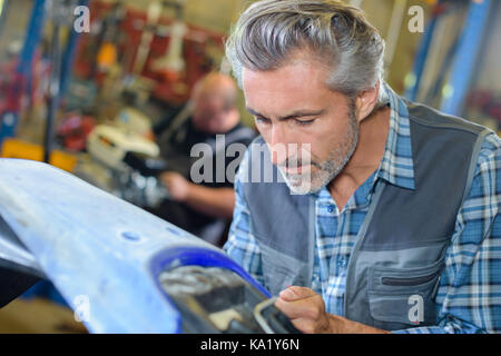 Ernster Mann sein Motorrad Reparatur in einer Garage. Stockfoto