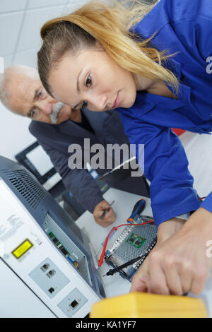 Weibliche mit Hilfe eines digitalen Multimeters auf der Hauptplatine Stockfoto