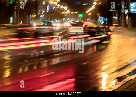 Unscharfes Bild der Stadt Verkehr in der Nacht auf nasser Straße Stockfoto